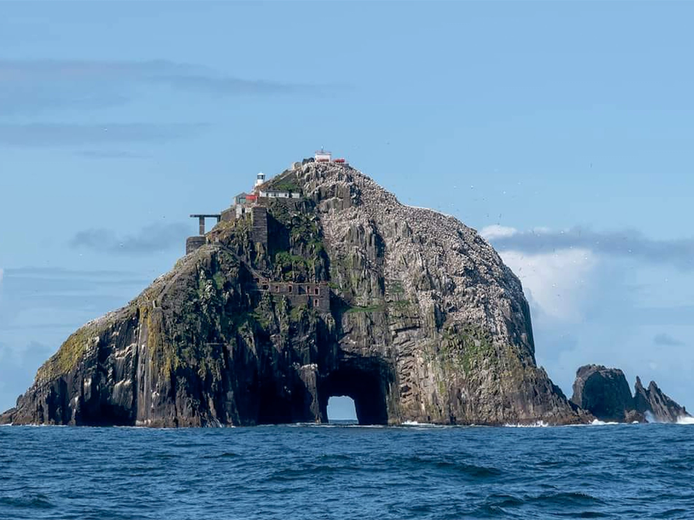 Approaching Bull Rock's natural tunnel, with the lighthouse in view perched on the rock